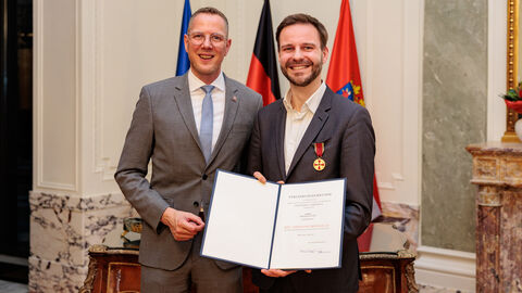 Staatssekretär Christoph Degen mit Sebastian Vogt und der Verdienstmedaille