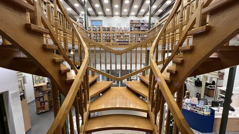 Zentralsicht auf die hölzerne Treppe mit dem ersten Stock der Stadtbücherei Korbach im Hintergrund