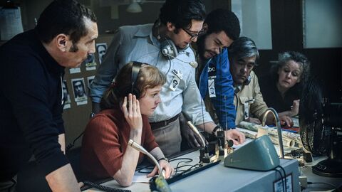 Szene aus September 5: Menschen stehen um ein Mischpult mit Mikrofonen herum, tragen teilweise Kopfhörer und schauen schockiert