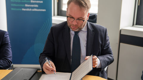 Minister Gremmels unterschreibt ein Schriftstück.