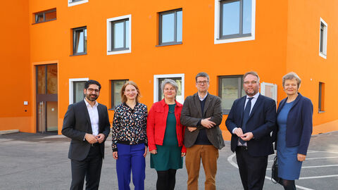 Minister Gremmels und Minister Mansoori stehen mit weiteren Vertreterinnen und Vertretern des Studierendenwerks Kassel und der Uni Kassel vor dem neuen Wohnheim.