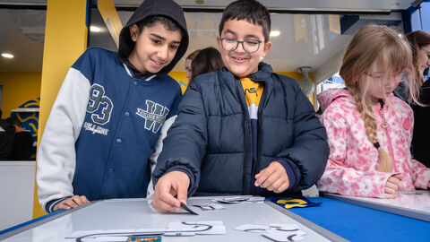 Insgesamt sollen auf der Tour rund 60.000 Schülerinnen und Schüler erreicht werden. Kinder beim Experimentieren.
