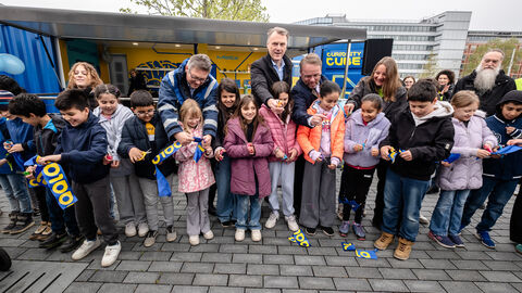„Gerade im MINT-Bereich brauchen wir dringend Fachkräfte, um die großen Herausforderungen unserer Zeit zu meistern", so Minister Gremmels. Minister Gremmels schneidet mit Kindern ein Band durch.