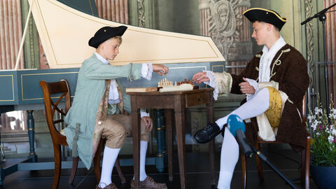 Impressionen von der Jubiläumsveranstaltung zu "Leben im Schloss". Zwei kostümierte Kinder auf der Bühne.
