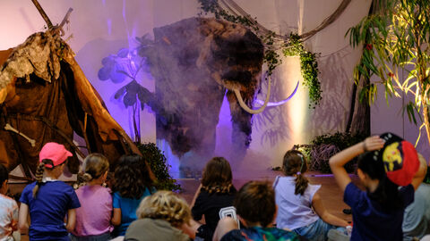 Szene aus einem Theaterstück, in dem ein Mammut auf der Bühne steht