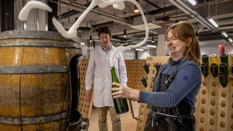 Impressionen aus der Hochschule Geisenheim: Einweihung des Getränketechnologischen Zentrums und Richtfest fürs Forschungszentrum für nachhaltigen und klimaangepassten Weinbau Eine Studentin füllt eine Flasche ab, dabei wirbelt Schaum auf
