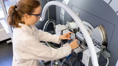 Im Exzellenzcluster „POLiS – Post Lithium Energy Storage“ werden die Grundlagen für Zukunftsbatterien erforscht. Eine Frau steht an einem wissenschaftlichen Apparat.