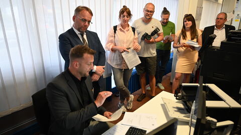 Minister Gremmels schaut einem Mitarbeiter über die Schulter beim Bearbeiten der E-Akte.