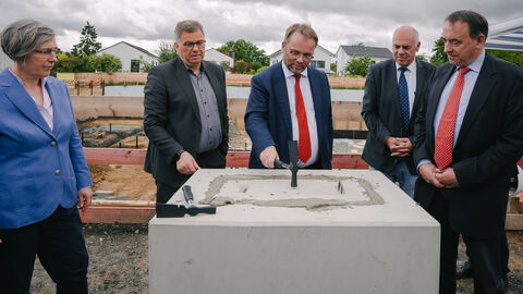 Minister Gremmels haut mit einem Hammer auf den Grundstein.