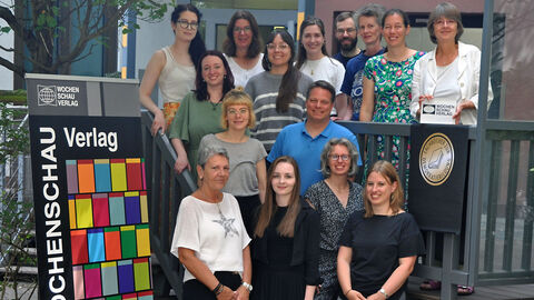 Mitarbeiter des Wochenschau Verlags stehen vor ihrem Gebäude.