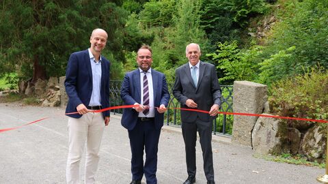 Justus Lange, Timon Gremmels und Thomas Platte durchschneiden ein rotes Band und weihen Brücke am Neuen Wasserfall ein