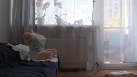 Szene aus "Monika": Ein Puppentorso auf einem Bett.