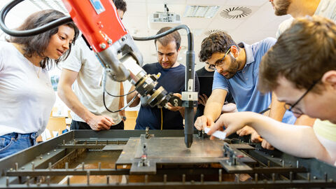 Ingenieure beugen sich über einen Roboterarm.