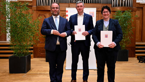 Staatsminister Timon Gremmels mit Prof. Dr. Sascha Feuchert und Dr. Anika Binsch, die den ersten Projektpreis beim Hessischen Hochschullehrpreis 2025 gewonnen haben.