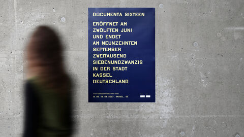 Eine Frau geht am neuen documenta-Plakat vorbei.