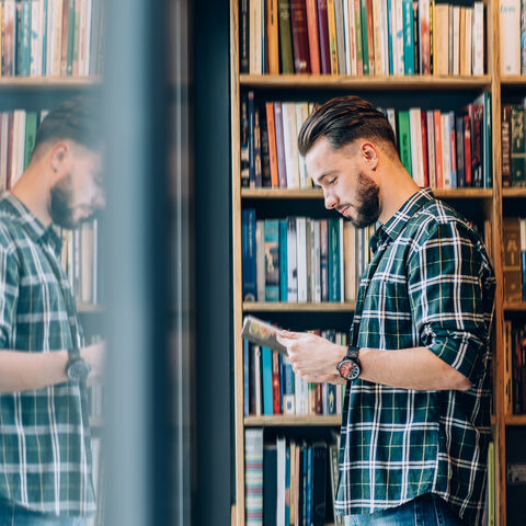 Hessen ist ein Land der Literatur Ein Mann steht vor einem Bücherregal und liest in einem Buch