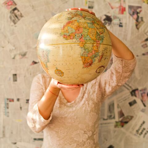 Hessens Hochschulen sind weltweit vernetzt. Eine Person hält einen großen Globus vors Gesicht